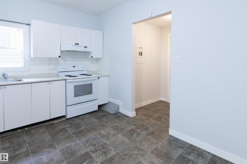Kitchen featuring white cabinets, electric stove, light countertops, under cabinet range hood, and backsplash - 11029 95 Street Nw, Edmonton, AB - Indoor Photo Showing Kitchen