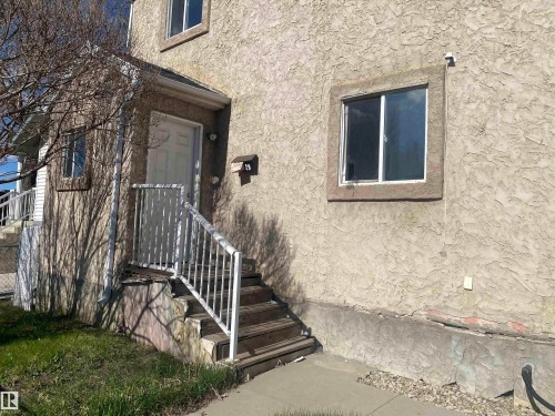 Stucco exterior featuring a white paneled door, exterior lighting, and an upper-level window - 11029 95 Street Nw, Edmonton, AB - Outdoor With Exterior