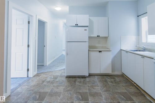 Kitchen with white cabinets, freestanding refrigerator, backsplash, and stone finish floors - 11029 95 Street Nw, Edmonton, AB - Indoor Photo Showing Kitchen