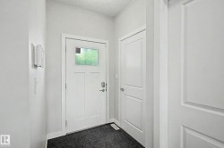 Bright entryway featuring a white six-panel entry door with transom window, polished chrome hardware, and dark tile flooring - 