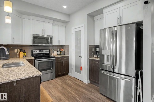 Kitchen featuring a stainless steel appliance package, dual-tone cabinetry, stone countertops, wood-finish flooring, and recessed lighting - 1783 Keene Crescent Sw, Edmonton, AB - Indoor Photo Showing Kitchen With Double Sink With Upgraded Kitchen