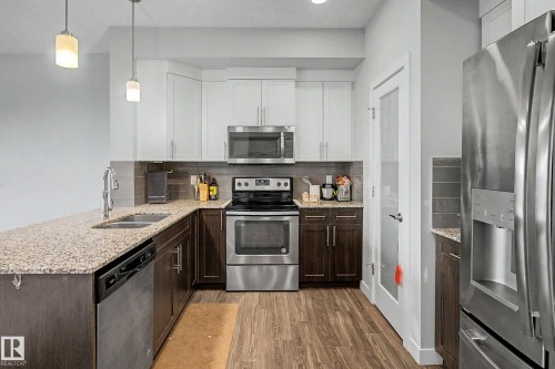Kitchen featuring granite countertops, stainless steel appliances, two-tone cabinetry, and wood-finish flooring - 1783 Keene Crescent Sw, Edmonton, AB - Indoor Photo Showing Kitchen With Double Sink With Upgraded Kitchen