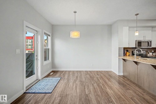 Wood-finish flooring, white walls, and a modern drum pendant light - 1783 Keene Crescent Sw, Edmonton, AB - Indoor Photo Showing Kitchen