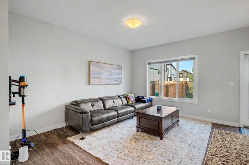 Wood-finish flooring throughout, a large window providing natural light, and a ceiling-mounted light fixture - 1783 Keene Crescent Sw, Edmonton, AB - Indoor Photo Showing Living Room
