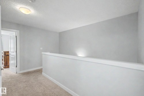 Carpeted hallway with a neutral color palette, featuring a semi-flush mount ceiling light fixture - 1783 Keene Crescent Sw, Edmonton, AB - Indoor Photo Showing Other Room