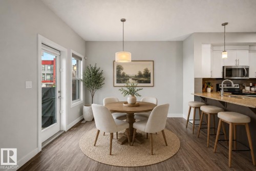 Open concept dining area with wood-finish flooring, a kitchen island with stone countertop, and white cabinetry - 1783 Keene Crescent Sw, Edmonton, AB - Indoor Photo Showing Dining Room