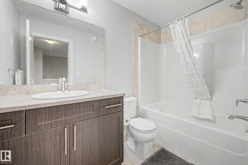 Bathroom featuring a vanity with dark wood-finish cabinetry, a light-toned countertop, a built-in sink, and a chrome faucet - 1783 Keene Crescent Sw, Edmonton, AB - Indoor Photo Showing Bathroom