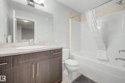 Bathroom featuring a vanity with dark wood-finish cabinetry, a light-toned countertop, a built-in sink, and a chrome faucet - 