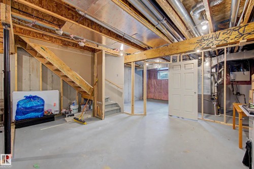 Spacious basement featuring exposed wooden beam ceiling, polished concrete flooring, and multiple room divisions with framed glass partitions - 1783 Keene Crescent Sw, Edmonton, AB - Indoor Photo Showing Basement