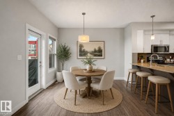 Open concept dining area with wood-finish flooring, a kitchen island with stone countertop, and white cabinetry - 