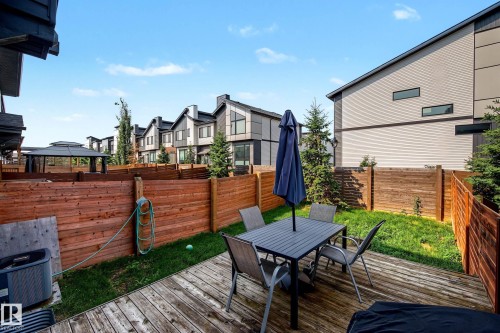 Spacious backyard featuring a wood deck, manicured lawn, and privacy fencing - 1783 Keene Crescent Sw, Edmonton, AB - Outdoor With Deck Patio Veranda With Exterior