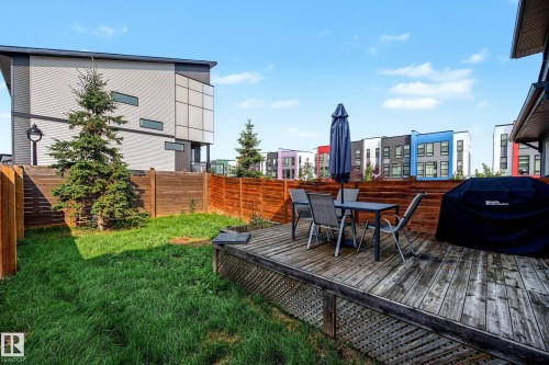 Expansive backyard featuring a manicured lawn, a wooden fence, and an elevated wood-finish deck - 1783 Keene Crescent Sw, Edmonton, AB - Outdoor