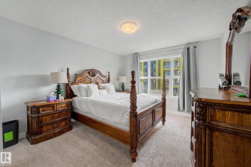 Primary bedroom featuring a four-poster wood bed with carved detailing, dual nightstands with multi-drawer storage, carpet flooring, recessed ceiling lighting, and glass doors opening to a secondary space with built-in cabinetry and natural light - 1783 Keene Crescent Sw, Edmonton, AB - Indoor Photo Showing Bedroom