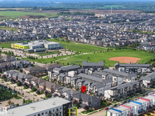 Aerial perspective showcasing a residential community with varied architectural styles, green spaces, and a school building - 1783 Keene Crescent Sw, Edmonton, AB - Outdoor With View