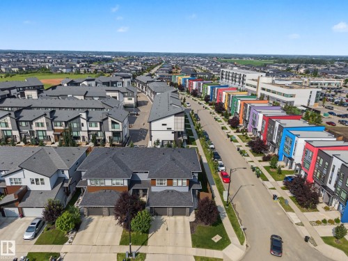 Modern residential development featuring varied architectural styles, a diverse color palette on some facades, paved roadways, and landscaped green spaces - 1783 Keene Crescent Sw, Edmonton, AB - Outdoor With View