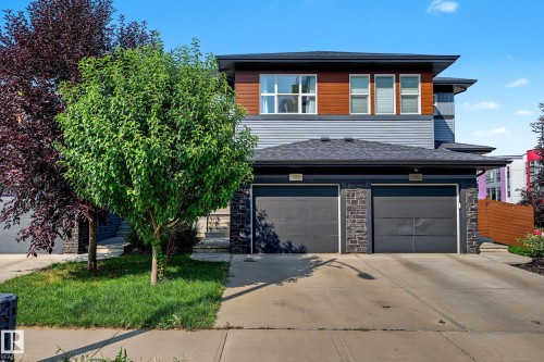 Modern two-story exterior featuring wood-finish siding, gray horizontal siding, and stone-clad pillars - 1783 Keene Crescent Sw, Edmonton, AB - Outdoor