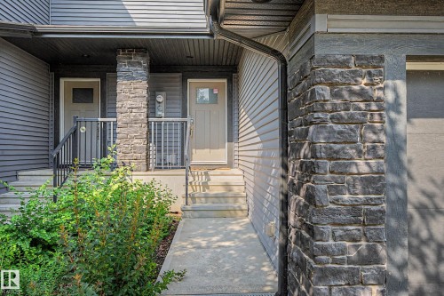 Welcoming entry featuring a stone and siding exterior, metal railings, and a covered entrance with direct access to the home - 1783 Keene Crescent Sw, Edmonton, AB - Outdoor