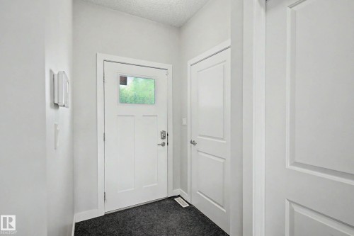 Bright entryway featuring a white six-panel entry door with transom window, polished chrome hardware, and dark tile flooring - 1783 Keene Crescent Sw, Edmonton, AB - Indoor Photo Showing Other Room