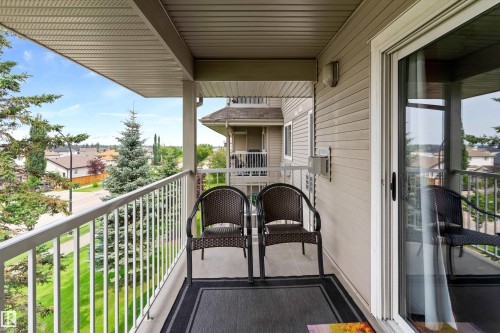 Elevated second-story deck featuring white aluminum railings, dark composite decking, and a covered overhang - #305A 6 Spruce Ridge Dr, Spruce Grove, AB - Outdoor With Balcony With Exterior