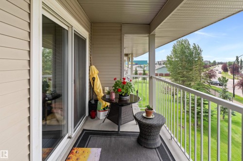 Covered balcony with aluminum railing overlooking manicured landscaping and open grounds - #305A 6 Spruce Ridge Dr, Spruce Grove, AB - Outdoor With Balcony With Exterior