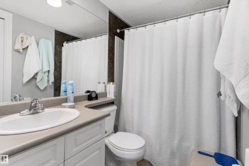 Modern bathroom featuring a curved vanity with an integrated sink, ample countertop space, and a large framed mirror - #305A 6 Spruce Ridge Dr, Spruce Grove, AB - Indoor Photo Showing Bathroom
