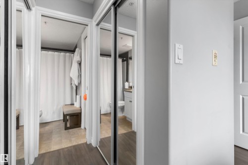 Spacious walk-in closet featuring mirrored sliding doors, wood-finish flooring, and ample shelving and hanging storage - #305A 6 Spruce Ridge Dr, Spruce Grove, AB - Indoor Photo Showing Other Room