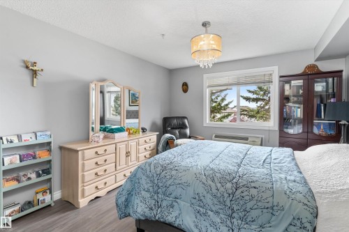 Wood-finish flooring, overhead chandelier, and a built-in display cabinet - #305A 6 Spruce Ridge Dr, Spruce Grove, AB - Indoor Photo Showing Bedroom