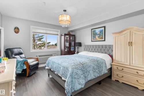 Wood-finish flooring with a ceiling-mounted light fixture - #305A 6 Spruce Ridge Dr, Spruce Grove, AB - Indoor Photo Showing Bedroom