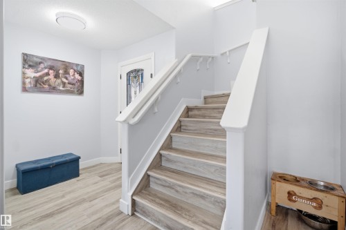 Entryway featuring wood-finish flooring, a staircase with white risers and wood-finish treads, and a front door with decorative glass - 714 87 Street Sw, Edmonton, AB - Indoor Photo Showing Other Room