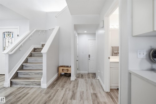 Two-story entryway featuring wood-finish flooring and a white staircase with matching handrails - 714 87 Street Sw, Edmonton, AB - Indoor Photo Showing Other Room