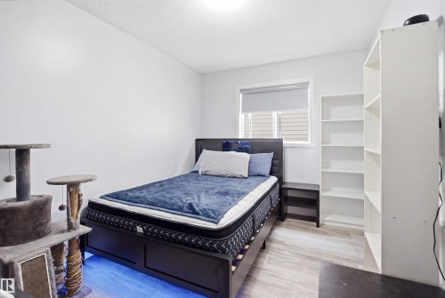 Bright room featuring light wood-finish flooring, a window with a roller blind, and white walls - 714 87 Street Sw, Edmonton, AB - Indoor Photo Showing Bedroom