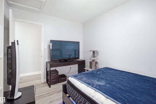 Light-toned wood-finish flooring provides a neutral backdrop for the bright white walls and ceiling - 714 87 Street Sw, Edmonton, AB - Indoor Photo Showing Bedroom