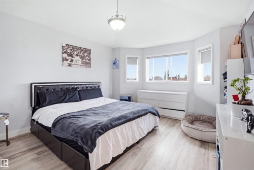 Spacious room featuring light wood-finish flooring and multiple windows providing ample natural light - 714 87 Street Sw, Edmonton, AB - Indoor Photo Showing Bedroom