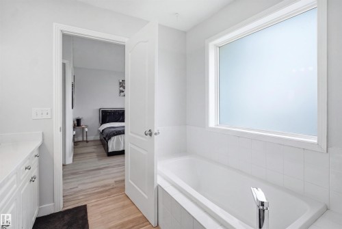 Built-in soaking tub with chrome faucet, featuring white subway tile surround and a privacy window - 714 87 Street Sw, Edmonton, AB - Indoor Photo Showing Bathroom