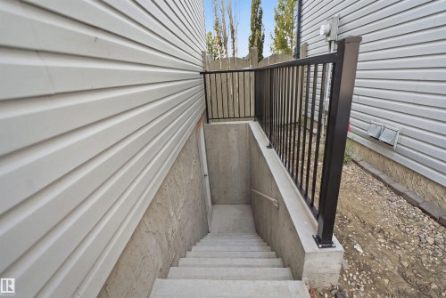 Concrete staircase leading to a lower level entrance, bordered by a black metal railing - 714 87 Street Sw, Edmonton, AB - Outdoor With Exterior