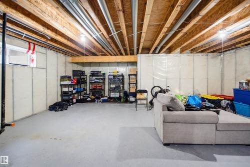 Unfinished basement space featuring exposed wood joists and ductwork, a small window, and concrete flooring - 714 87 Street Sw, Edmonton, AB - Indoor Photo Showing Basement