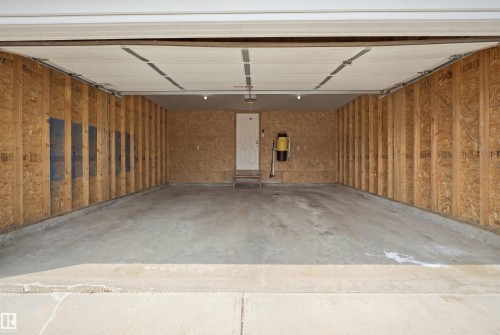 Spacious two-car garage featuring a concrete floor, framed walls, and an overhead door - 714 87 Street Sw, Edmonton, AB - Indoor Photo Showing Garage