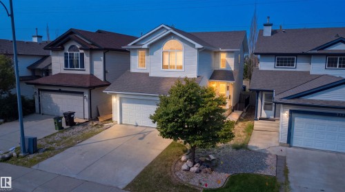 Two-story residence featuring light-colored siding, a prominent arched window, and an attached two-car garage - 714 87 Street Sw, Edmonton, AB - Outdoor With Facade