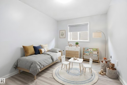 Bedroom featuring light-toned wood-finish flooring, white walls, and a window with roller blinds - 714 87 Street Sw, Edmonton, AB - Indoor Photo Showing Other Room