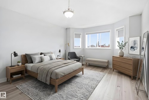 Spacious bedroom featuring light wood-finish flooring, a bay window with multiple panes, and a semi-flush mount ceiling light fixture - 714 87 Street Sw, Edmonton, AB - Indoor Photo Showing Bedroom