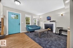 Welcoming foyer with turquoise entry door featuring transom window, wide-plank wood-finish flooring throughout, and abundant natural light from multi-pane glass doors - 