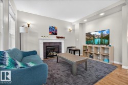 Sophisticated living room featuring a gas fireplace with dark surround, recessed ceiling lighting, and brass wall sconces - 