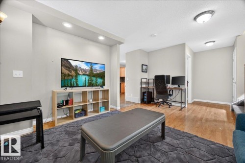Versatile recreation room featuring engineered wood-finish flooring, recessed ceiling lighting, and built-in shelving with cubbies for storage and display - 887 Oakland Boulevard, Devon, AB - Indoor With Fireplace