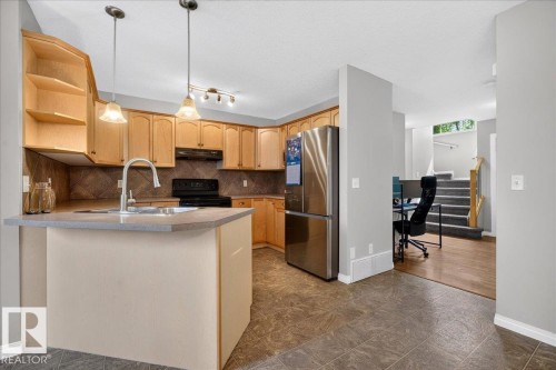 Kitchen featuring wood cabinetry, stainless steel refrigerator, and integrated kitchen island - 887 Oakland Boulevard, Devon, AB - Indoor Photo Showing Kitchen With Double Sink
