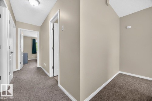 Bright hallway with neutral taupe walls, white trim, and plush carpeting throughout - 887 Oakland Boulevard, Devon, AB - Indoor Photo Showing Other Room