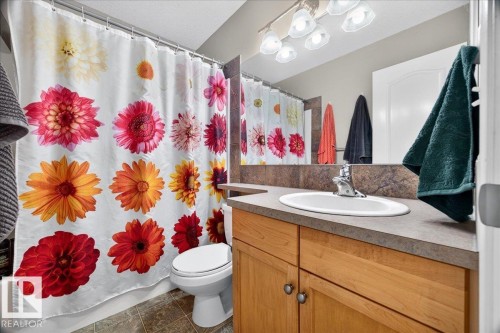 Vanity with integrated sink, wood-finish cabinetry, and brushed nickel hardware - 887 Oakland Boulevard, Devon, AB - Indoor Photo Showing Bathroom