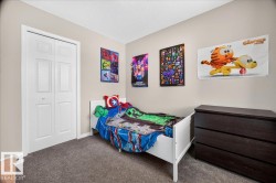 Bedroom featuring carpet flooring, white six-panel closet doors, and dark wood dresser - 