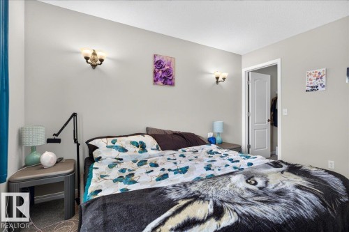Comfortable bedroom featuring neutral wall finishes, dual wall-mounted light fixtures, and carpeted flooring - 887 Oakland Boulevard, Devon, AB - Indoor Photo Showing Bedroom