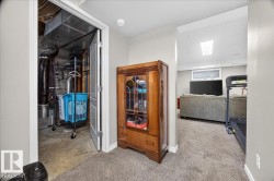 Utility room featuring organized storage with white-framed door, wood-finish cabinet with glass panels, concrete flooring, and access to mechanical systems - 