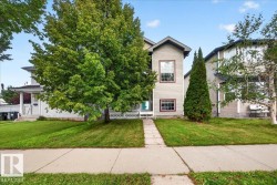 Two-story residence featuring neutral siding exterior, symmetrical facade with multi-pane windows, and a welcoming front entrance - 